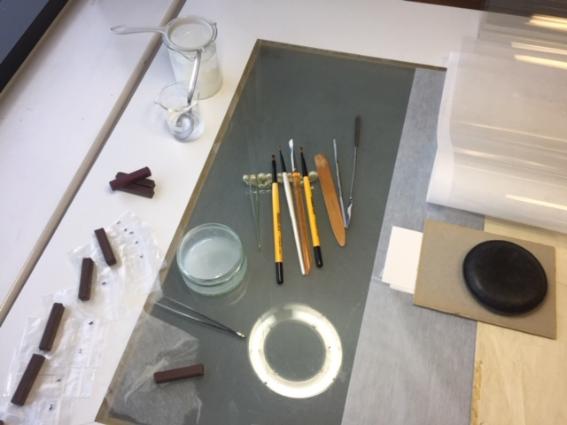 Tools and brushes alongside a plan on a lightbox during treatment.